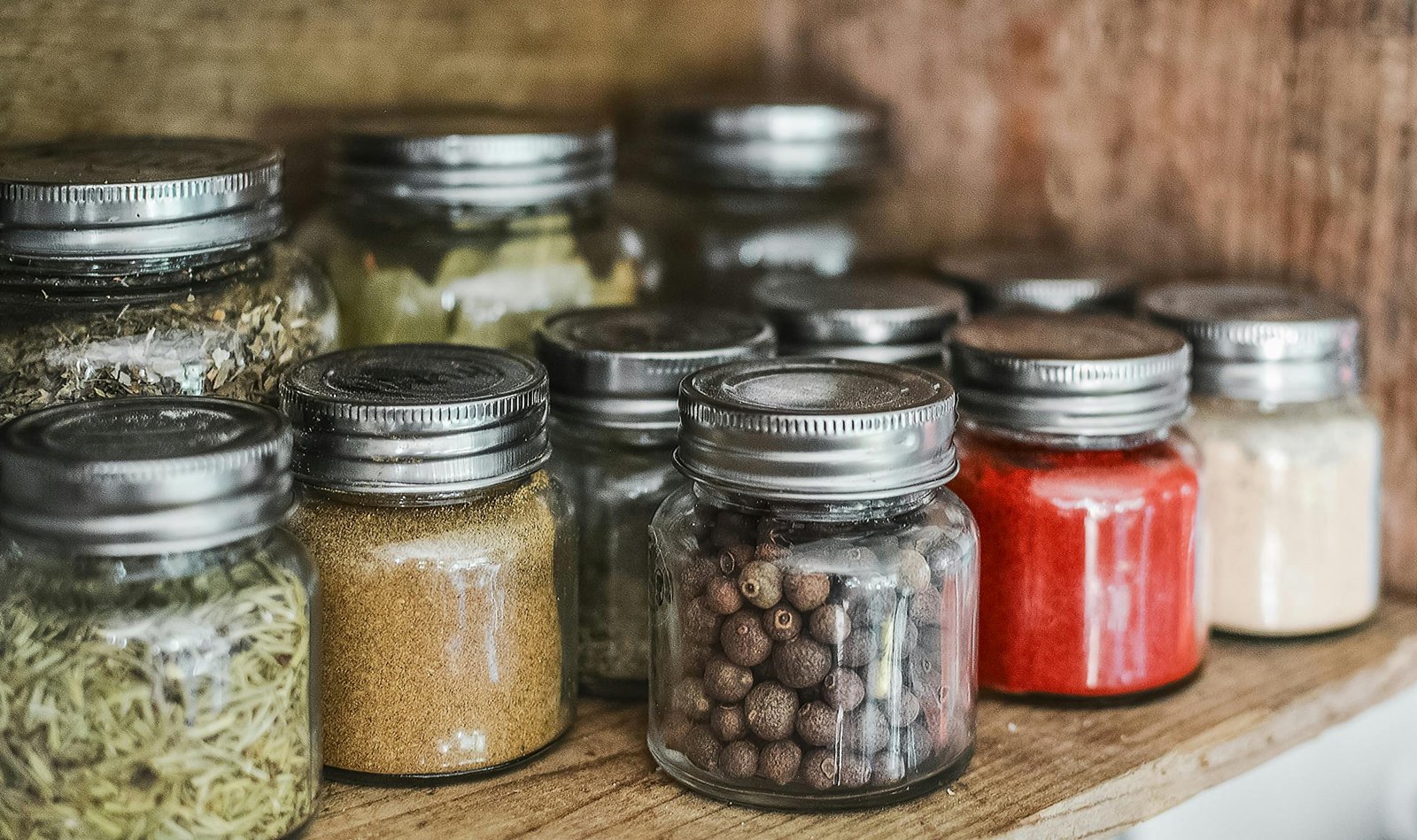 pexels-photo-531446-531446 Close-up of assorted spice jars with various herbs on a kitchen shelf, showcasing colorful culinary ingredients.
